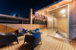 An outdoor patio area with seating and a glass door leading to an interior staircase. - 3BR Roma Norte Penthouse w/ Private Rooftop (Ciudad de México)