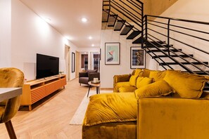 A modern living room with a sofa, a television, and a staircase. - 3BR Roma Norte Penthouse w/ Private Rooftop (Ciudad de México)