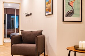 A modern living room with a brown armchair, a small round table with candles, and a framed painting of a bird on the wall. - 3BR Roma Norte Penthouse w/ Private Rooftop (Ciudad de México)