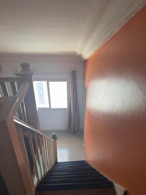 A staircase leading to a landing with a view of a window and curtains.