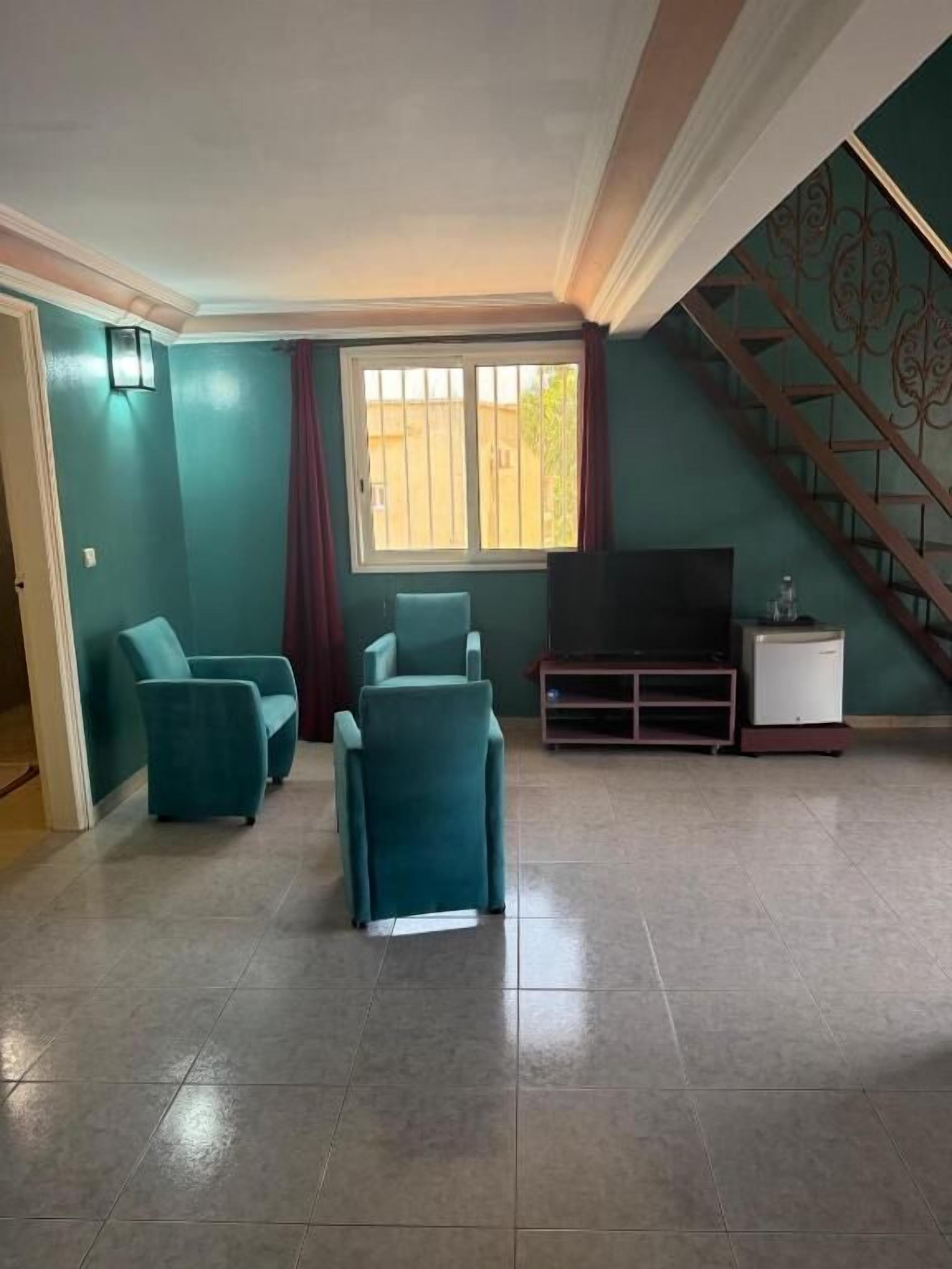 A living room with teal walls, a staircase, and a television on a stand.
