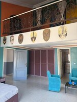 Una habitación de hotel con balcón, cama, un sillón azul y una mesita de centro.