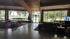 A spacious indoor area with a high ceiling, large windows, and a seating area with couches and tables.