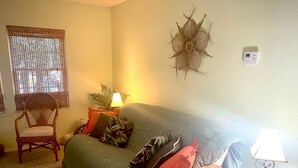 A living room with a sofa, a chair, a small table with a lamp, and a decorative wall piece.