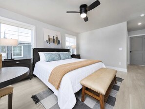A bedroom with a bed, bedside tables, a ceiling fan, and a window. - Haven House | 5 min walk to beach • pool • grill (South Haven)