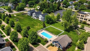 Ett bostadsområde med en swimmingpool som är omgiven av ett staket, hus och träd.