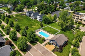 A residential area with a swimming pool surrounded by a fence, houses, and trees. - Haven House | 5 min walk to beach • pool • grill (South Haven)