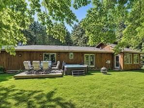 Ein Holzhaus mit Terrasse, Sitzgelegenheiten im Freien und Whirlpool.