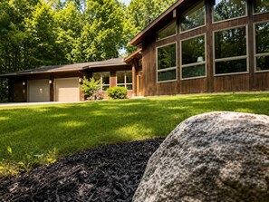 A modern two-story house with a garage, large windows, and a well-maintained lawn. - Wildhaus Retreat | Hot Tub • Private Walking Trail (South Haven)