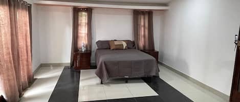 Une chambre à coucher avec un lit, des tables de chevet et des rideaux.