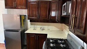 A kitchen with dark wooden cabinets, a stainless steel refrigerator, a white stove, and a microwave on the countertop. - Charming 4-bedroom house in Managua perfect for your getaway near everything ! (Managua)