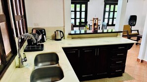 A kitchen with a double sink, a coffee maker, and a dining area with chairs and a table. - Charming 4-bedroom house in Managua perfect for your getaway near everything ! (Managua)