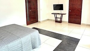 A bedroom with a bed, a television, and two doors. - Charming 4-bedroom house in Managua perfect for your getaway near everything ! (Managua)