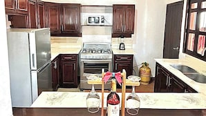 A kitchen with dark wooden cabinets, a stainless steel refrigerator, a gas stove, and a sink. - Charming 4-bedroom house in Managua perfect for your getaway near everything ! (Managua)