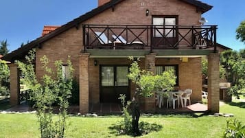 Ein zweistöckiges Ziegelhaus mit Balkon, überdachter Veranda und Rasen.