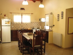 A compact kitchen with a dining table, chairs, a refrigerator, a microwave, and a stove.