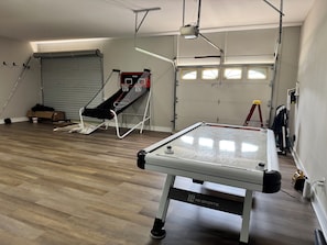 A billiards table with a netted enclosure, a basketball hoop, and a window with blinds. - Lake House, Boating, Kayaking, Huge backyard (Hartwell)