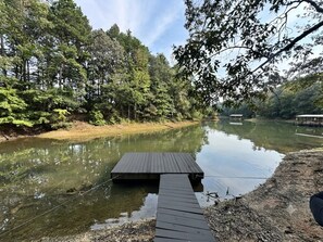 A wooden dock extending into a calm lake surrounded by dense forest.
