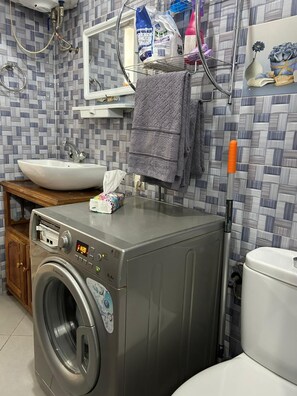 A compact bathroom with a washing machine, a sink, and a toilet. - Apartment in Agadir (Agadir)