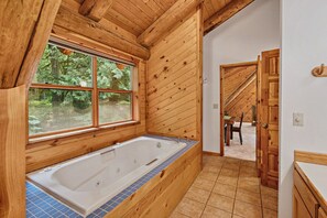 Interior de madera con una bañera grande, un ventanal y una puerta que da a una escalera.