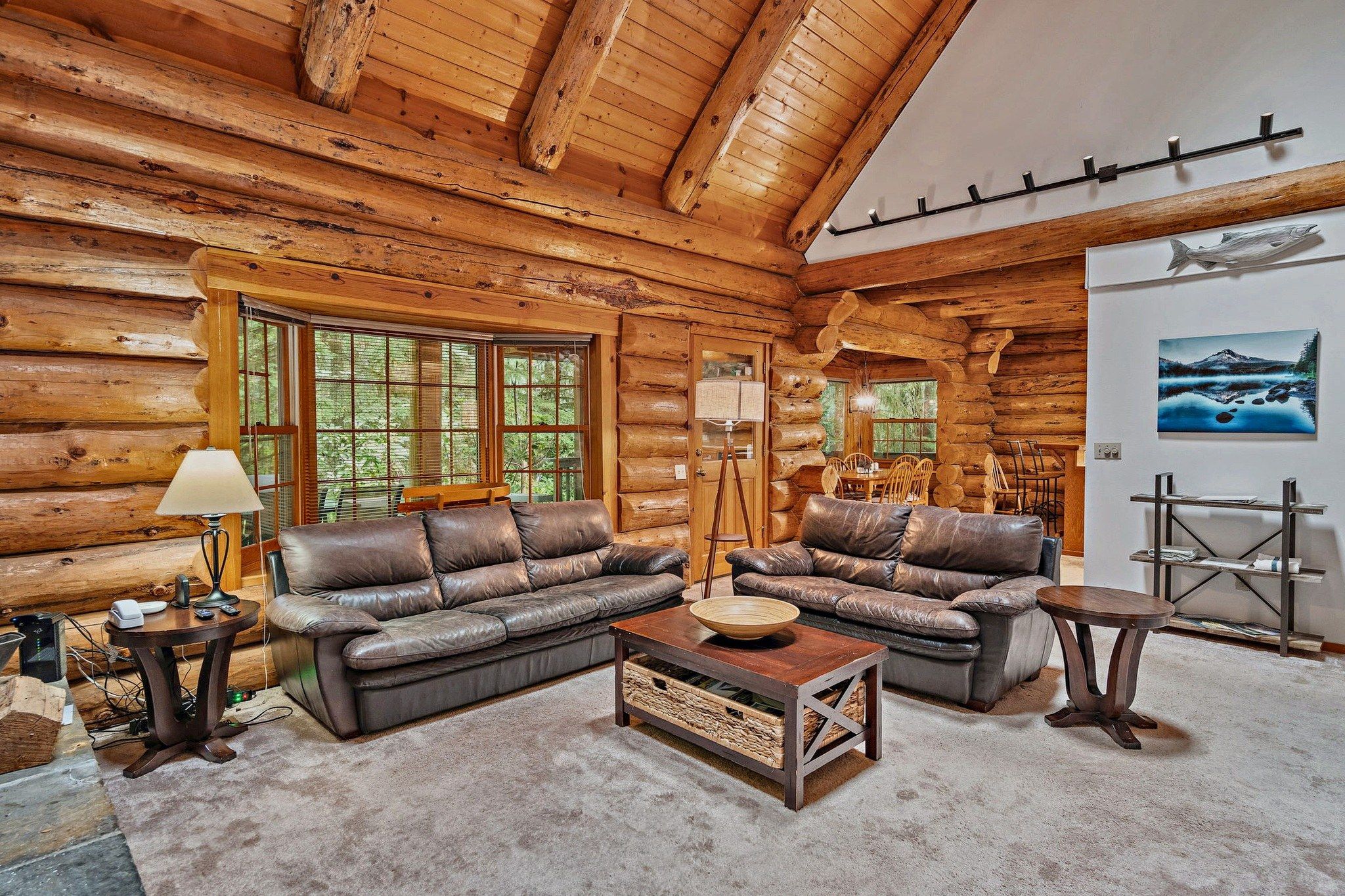 A log cabin interior with a sectional sofa, a coffee table, and a dining area.