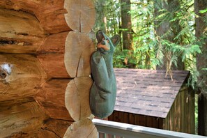 A wooden structure with a carved animal figure, surrounded by trees and a wooden fence.
