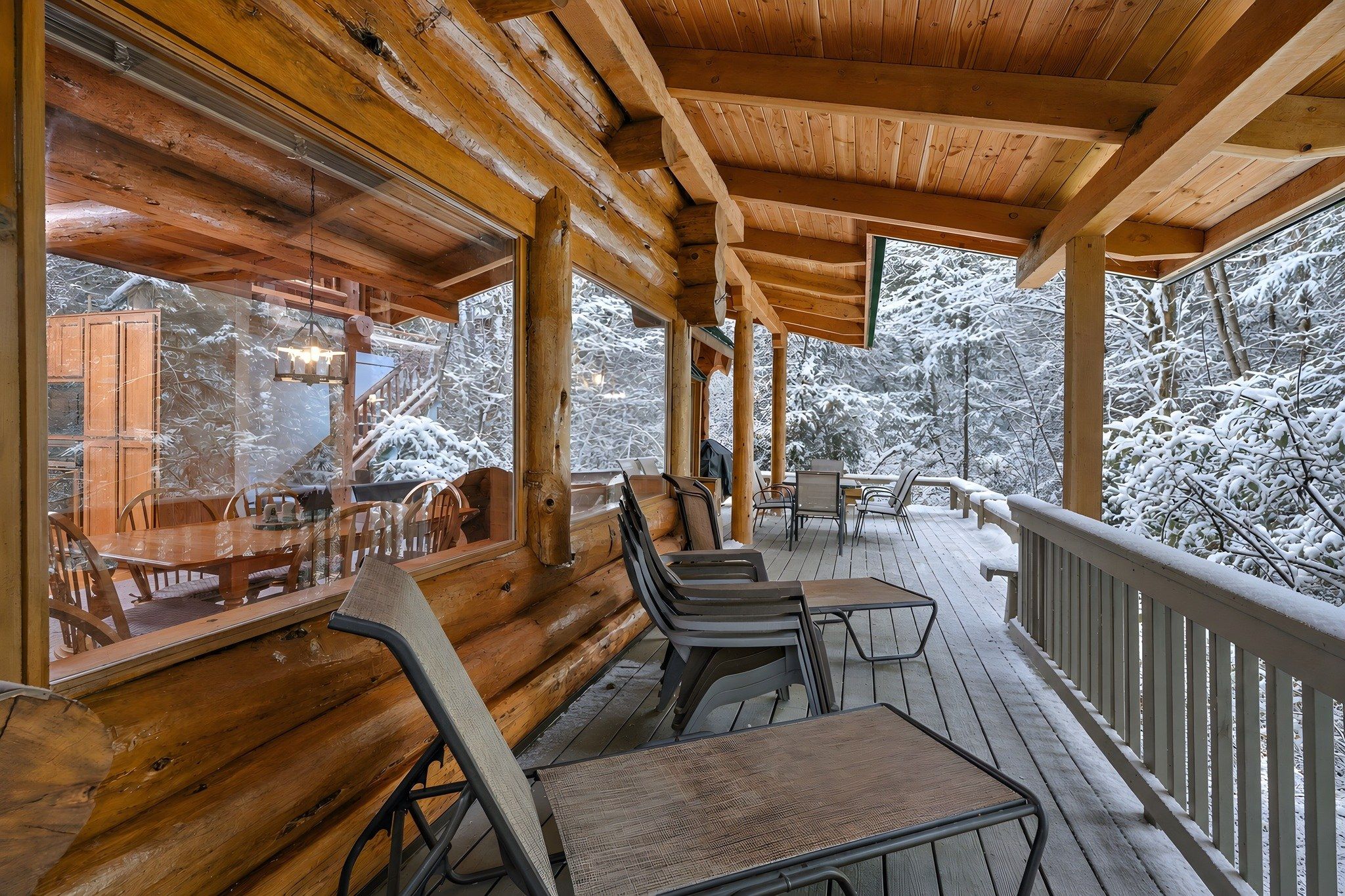 A wooden deck with a covered seating area, overlooking a snowy landscape.
