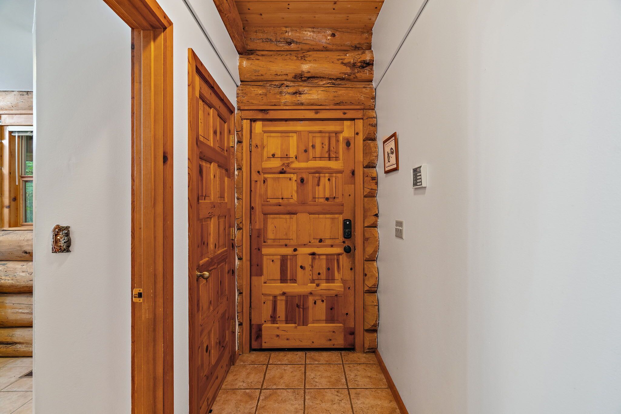 Un couloir avec une porte en bois, un mur en pierre et un sol carrelé.