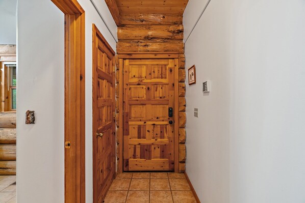 A hallway with a wooden door, a stone wall, and a tiled floor.