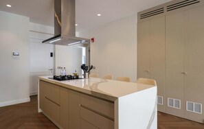 Cuina moderna amb una illa central, electrodomèstics integrats i un armari ampli.