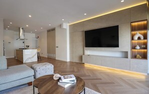 A modern living room with a sofa, ottoman, coffee table, and a flat-screen TV mounted on a wall. - w* | Enjoyable 2BR Stay w/ Balcony in Miraflores (Lima)