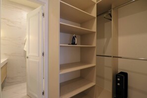 Ein begehbarer Kleiderschrank mit offenen Türen, der Regale und Ablageflächen zeigt.