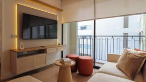 A modern living room with a flat-screen TV mounted on the wall, a wooden console table, a sofa with cushions, and a small round table with a book. - w* | Designer 2BR Stay w/ Balcony in Miraflores (Lima)