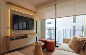 A modern living room with a flat-screen TV mounted on the wall, a wooden console table, a sofa with cushions, and a small round table with a book.