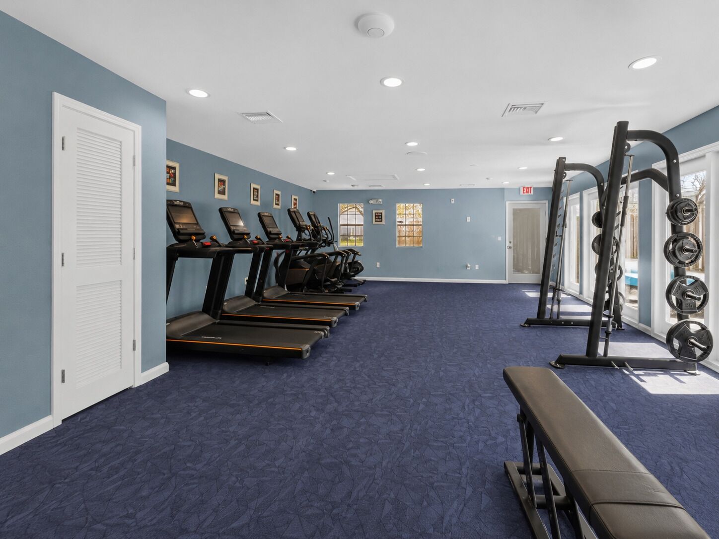 Une salle de remise en forme équipée de tapis de course, d’un banc et de matériel de musculation.