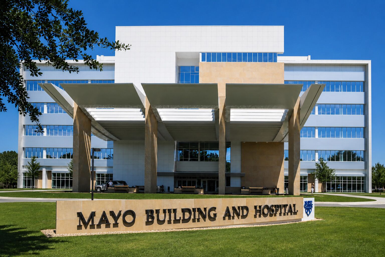 Le bâtiment et l’hôpital Mayo, avec un ciel dégagé, une grande entrée ornée de colonnes et un panneau indicateur.