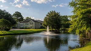 A residential building with a pond and fountain, surrounded by trees and grass. - Serene Mins 2 Sand Beach Brookdale Mayo Clinic Everbank (Jacksonville)