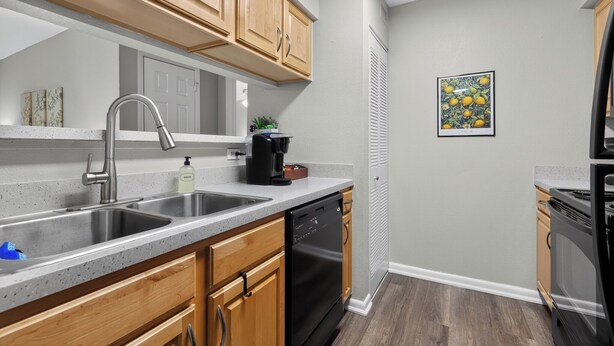 A kitchen with wooden cabinets, a stainless steel sink, a dishwasher, and a coffee maker. - Serene Mins 2 Sand Beach Brookdale Mayo Clinic Everbank (Jacksonville)