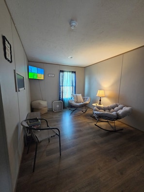 A modern living room with a flat-screen TV, a sofa, a rocking chair, and a standing fan. -  5-bedroom mobile home, 5 miles to Grand Lake. Close to Disney OK Rock Crawling  (Jay)