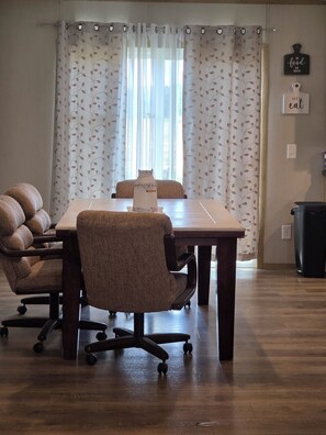 A conference room with a wooden table, two upholstered chairs, a vase on the table, and a curtain with a leaf pattern. -  5-bedroom mobile home, 5 miles to Grand Lake. Close to Disney OK Rock Crawling  (Jay)