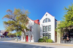 A white building with a red roof, a red door, and a large window. - Historic Charleston Right Outside Your Front Door (Charleston)