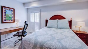 Ein Schlafzimmer mit Bett, Schreibtisch, Stuhl und Nachttischen.