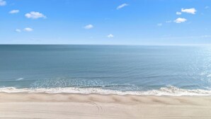 Una playa con cielo despejado y mar tranquilo.