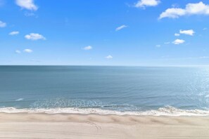 En strand med klar himmel og roligt hav.