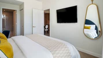 Une chambre d’hôtel équipée d’un lit, d’une télévision, d’un miroir et d’une porte donnant accès à une salle de bain.