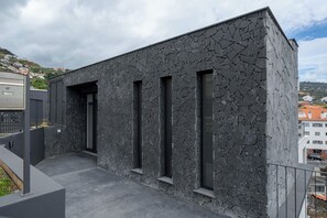 A modern building with a textured facade and three vertical windows.