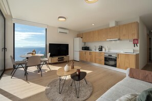 Een moderne woonkamer met televisie, een eethoek en keuken.