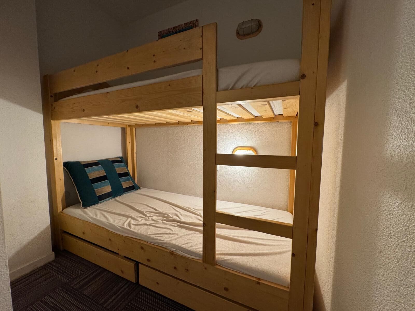 Una cama litera con estructura de madera, un colchón y una almohada.