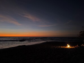 A beach at dusk with a campfire. - Pura Vida - Tamarindo (Tamarindo)