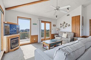 A living room with a fireplace, sofa, and a television. - The Final View | 750 ft to the beach | Private Pool, Hot Tub, and Dog Friendly (Corolla)
